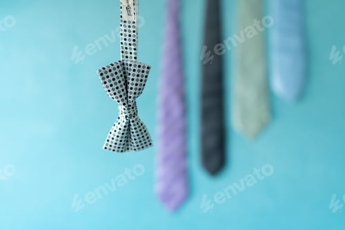 Preview: Close up of a bow tie in front of a light blue background with gradual arranged ties