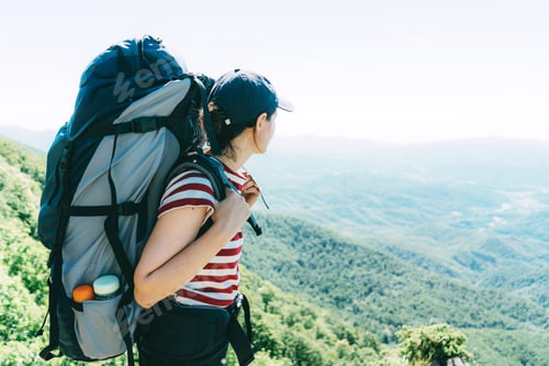 Woman with Backpack Enjoys Mountain Vista on Sunny Day