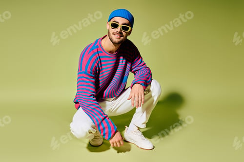 Preview: Stylish young man showcases vibrant fashion sense in trendy studio setting