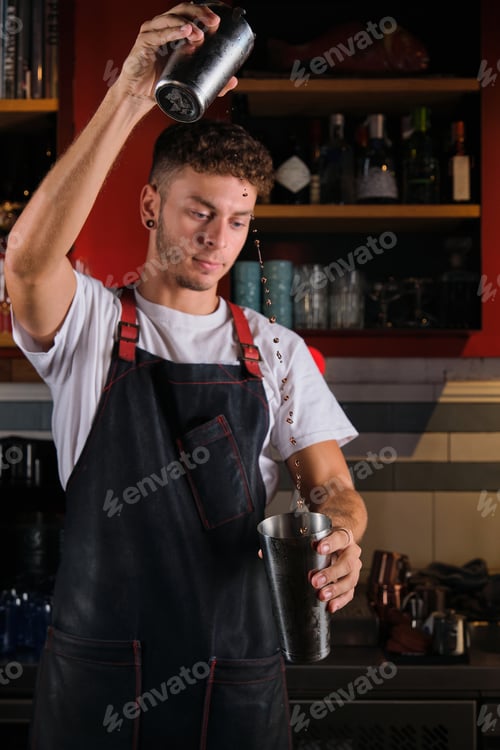 Preview: Focused man mixing drink in bar