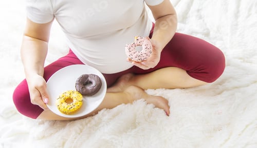 Preview: A pregnant woman eats sweet donuts. Selective Focus.