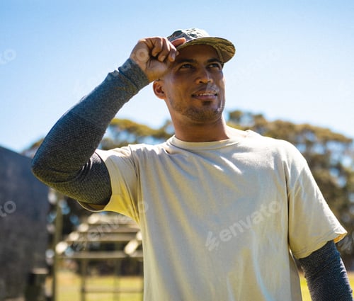 Preview: Man in outdoor bootcamp adjusting cap, ready for fitness training, copy space