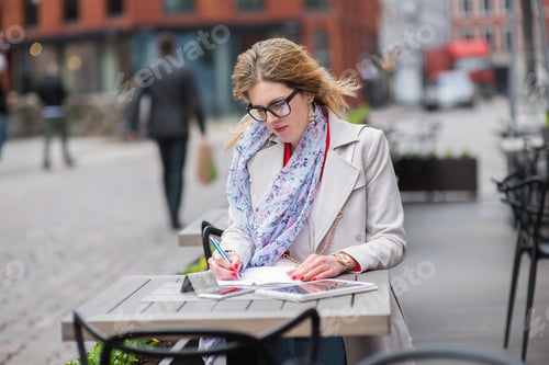 Preview: A beautiful business woman sitting in an outdoor cafe and preparing papers for business conferences