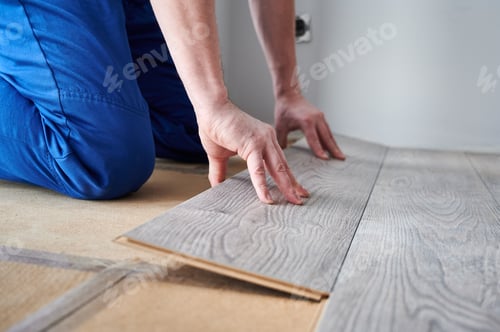 Preview: Male worker hands laying laminate flooring in apartment.