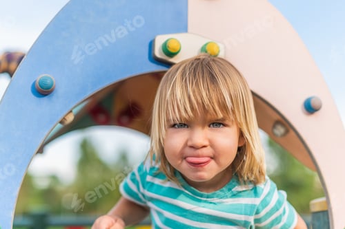 Preview: naughty little boy sticking his tongue out in the playground