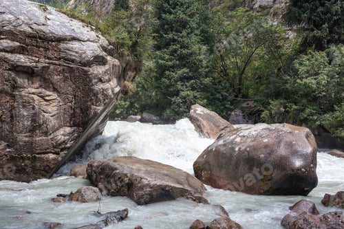 Preview: A beautiful stormy mountain river of milky hue flows rapidly among large stones