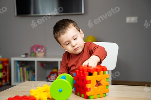 Preview: A cute attentive little toddler boy of two years old sits at a children's table
