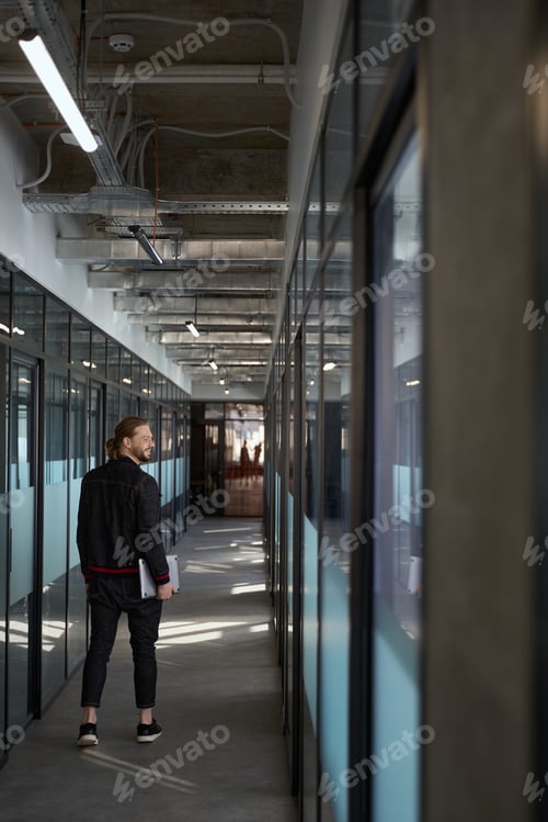 Preview: Happy male worker walking down corridor indoors