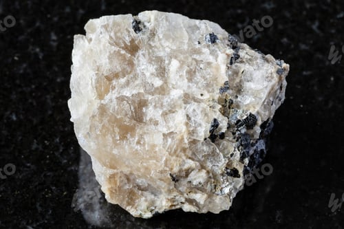 Preview: sample of raw cryolite rock on black granite