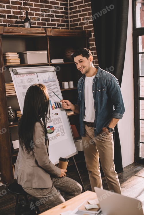 Preview: couple of colleagues discussing project using marketing graph in loft office