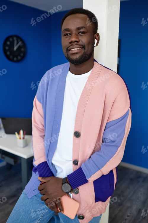 Preview: Modern black man wearing colorful clothes in office and smiling at camera