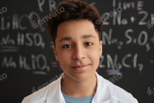 Preview: Multiethnic teen boy wearing lab coat in science class looking at camera
