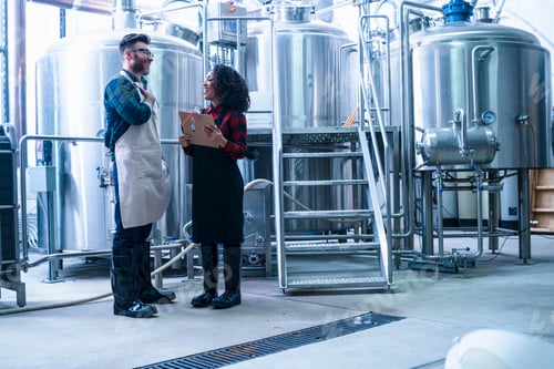 Preview: Colleagues in brewery holding clipboard face to face smiling