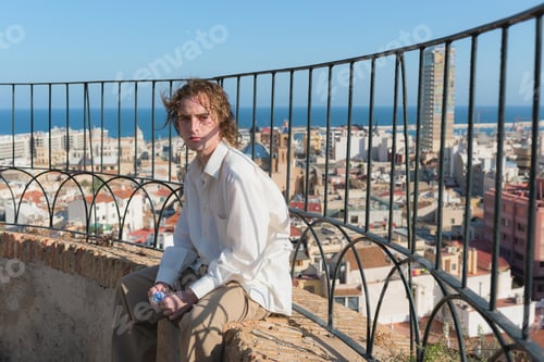 Preview: Young man in a white shirt looking at the camera with the city of Alicante in the background
