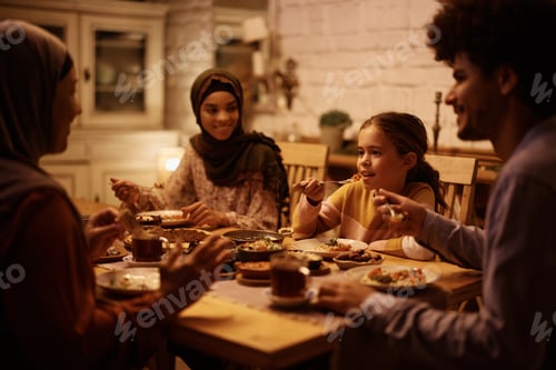 Preview: Multigeneration Muslim family eating dinner together at dining table.