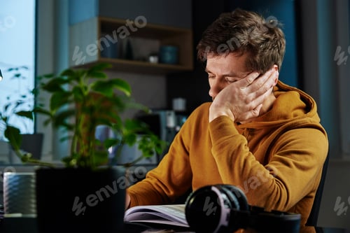 Preview: Tired man works late at workplace in the night