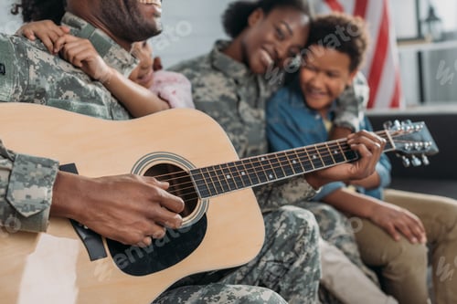 Preview: Woman and children listening to father in camouflage clothes playing guitar