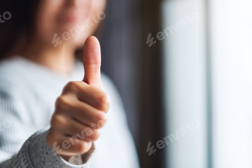 Preview: Closeup image of a woman making and showing thumbs up hand sign