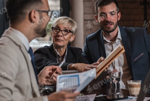 Preview: Senior businesswoman holding a meeting with her younger colleagues at office cafeteria.