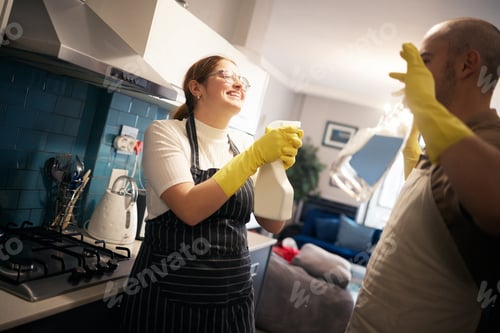 Preview: I surrender I promise. Shot of a young couple playing while they clean their kitchen.