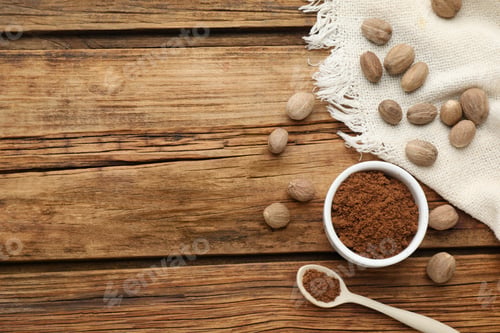 Preview: Ground nutmeg and whole seeds on wooden table, flat lay. Space for text