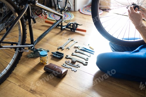 Preview: Young man repairing a bicycle at home. Mechanic serviceman repairman installing assembling or adjust