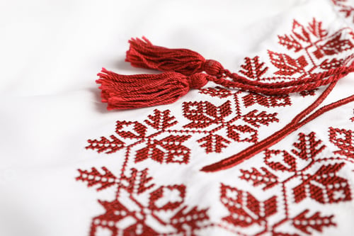 Preview: Beautiful red Ukrainian national embroidery on white fabric, closeup