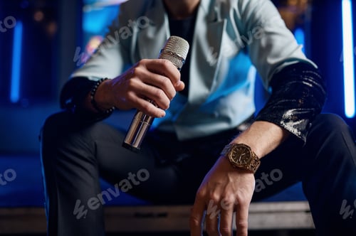 Preview: Cropped shot of male pop singer hand holding microphone