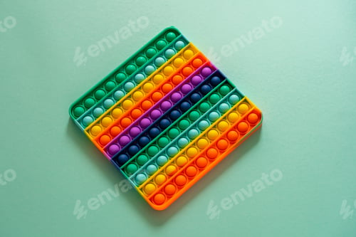 Preview: Bright silicone striped toy big Pop It closeup on blue background. Popit for kids playing with