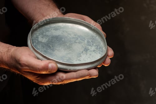 Preview: Male hands holding empty plate on dark background, lack of food, hunger concept.