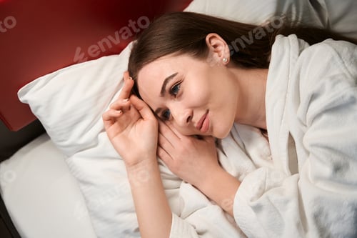 Preview: Pleased female daydreaming in bedroom after waking up
