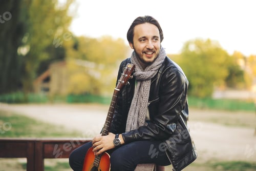 Preview: Young man playing on guitar at the lake