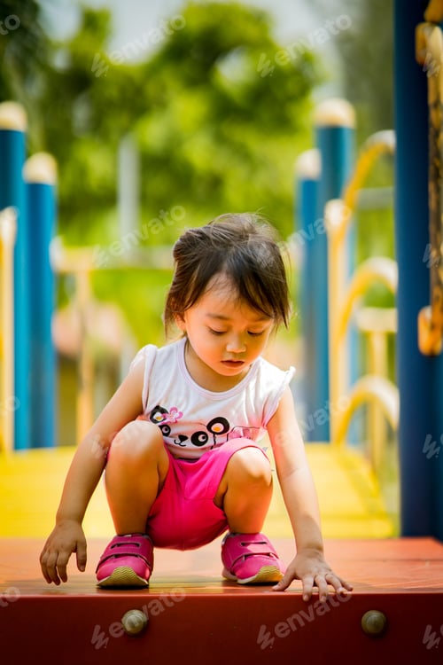 Preview: toddler girl squatting while playing at the playground outdoor