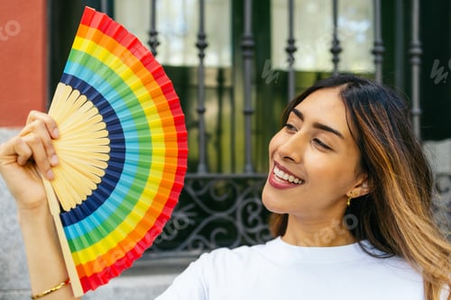 Preview: Young woman waving rainbow fan celebrating lgbtqia plus pride month