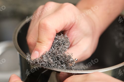 Preview: Cropped image of man hands washing a pot or doing the dishes with a stainless steel sponge scrubber