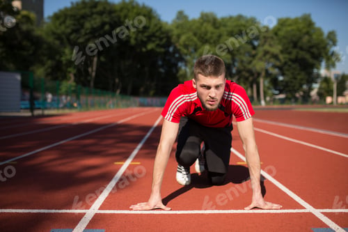 Preview: Concentrated sportsman thoughtfully looking forward in starting position ready to start running