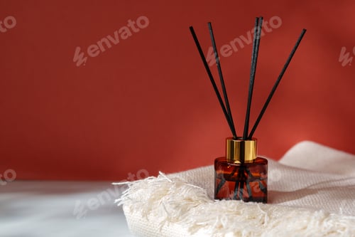Preview: Elegant Reed Diffuser on White Textured Surface With Warm Red Backdrop