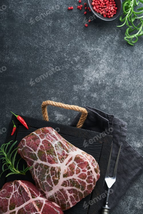 Preview: Steaks Raw. Raw cowboy steak, marbled beef meat with spices rosemary and pepper on black wooden boar