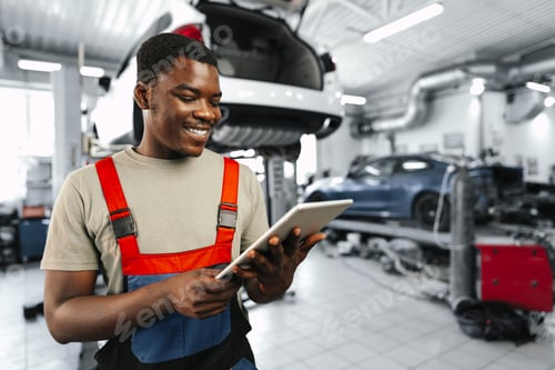 Preview: Young African auto mechanic using digital tablet in a car service