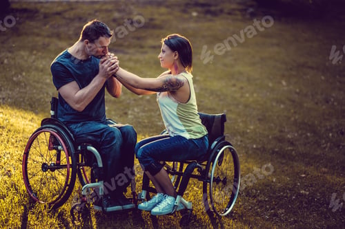 Preview: Handicapped young couple on two wheelchairs kissing .