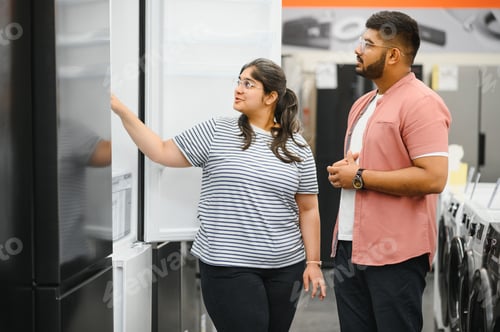 Preview: Indian family couple buying domestic refrigerator in supermarket.