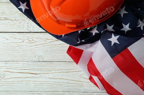 Preview: American flag and hard hat on white wooden background, space for text