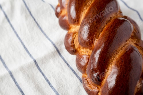 Preview: Homemade jewish challah bread on a white wooden surface, side view. Copy space.