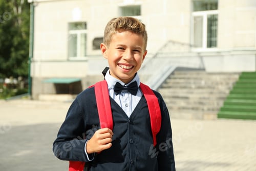 Preview: Boy with backpack against school building, space for text