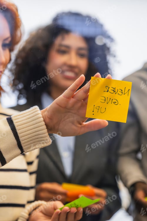 Preview: Coworkers brainstorming and sharing ideas with sticky notes on glass wall