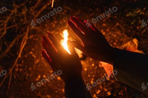 Preview: Hands warming by a fire during a night camping trip in the woods