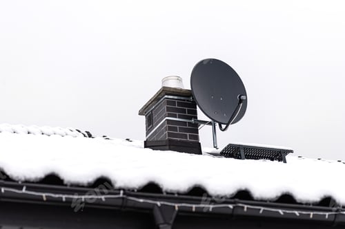 Preview: The roof of a single-family house is covered with snow against a cloudy sky.