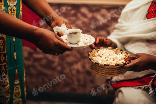 Preview: African women's hands holding a cup of coffee and straw bowl with popcorn