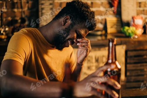 Preview: Happy young man laughing and holding beer bottle lifestyle picture.