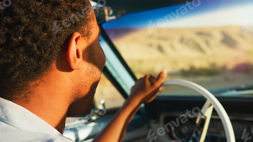 Preview: Close Up Of Man Driving Classic Open Top Car On Road Trip Through Countryside At Sunset